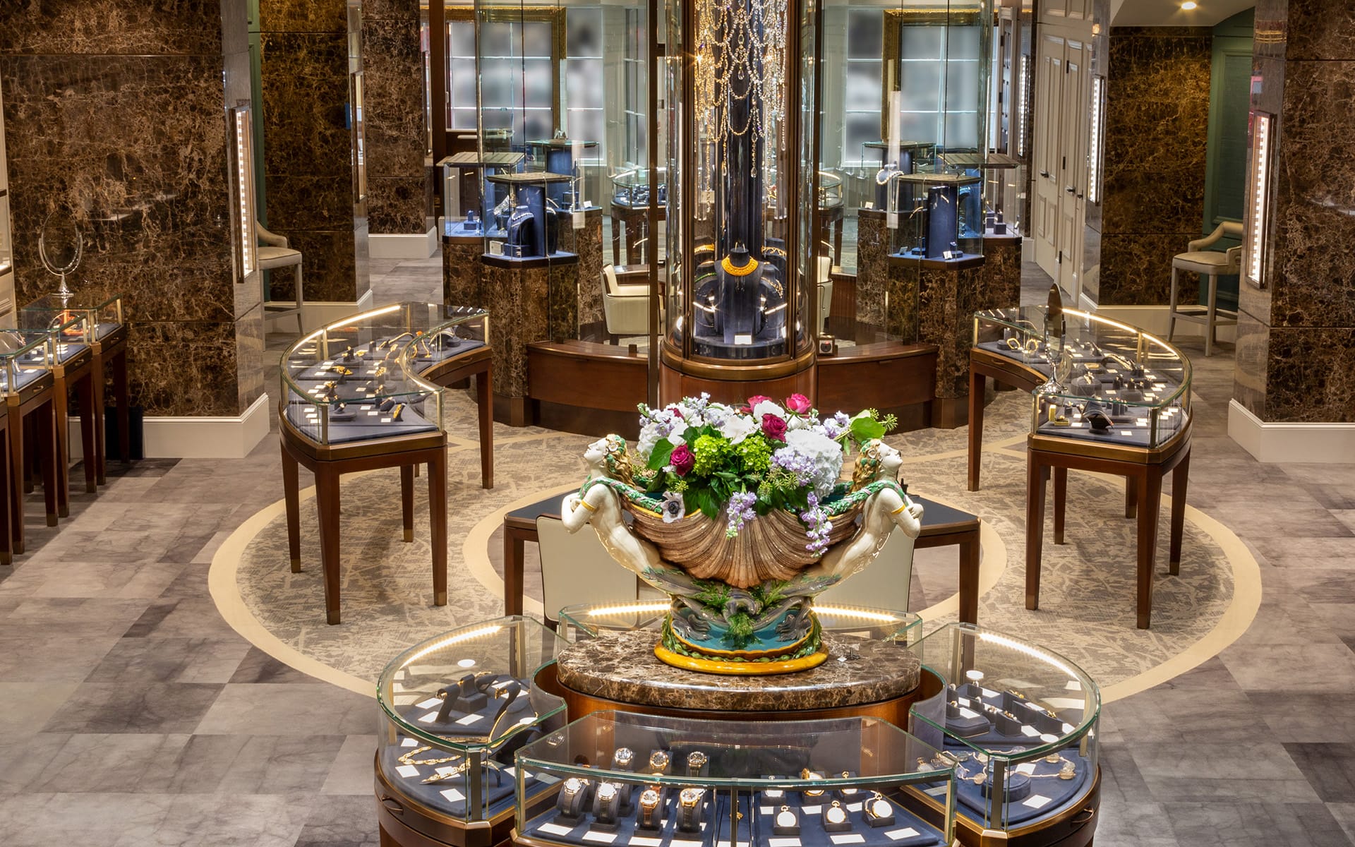 Luxury jewelry store interior with elegant display cases, featuring a large floral arrangement in the center.