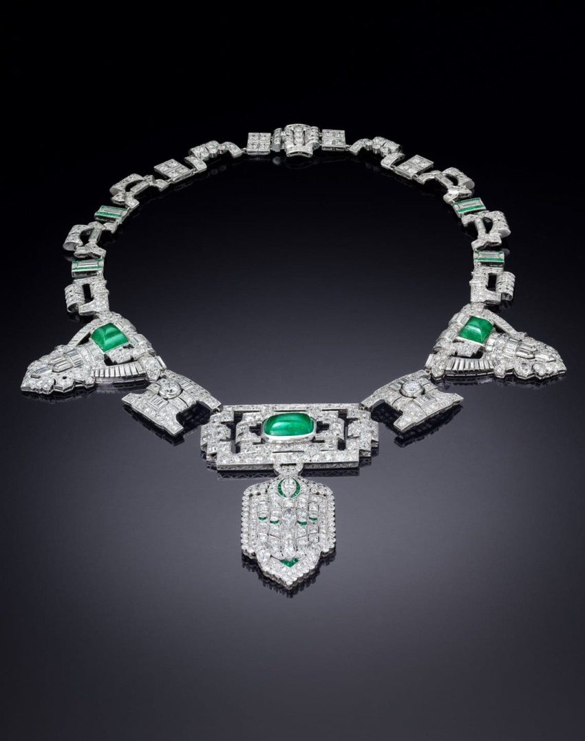 Art Deco necklace with emerald and diamond detailing displayed on a dark background.