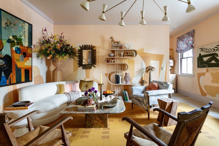 Eclectic living room with modern art, wooden furniture, bookshelves, floral arrangements, and a unique coffee table display.