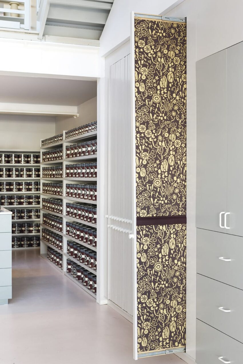 Stylish storage room with patterned sliding door in foreground, shelves filled with neatly organized jars in the background.