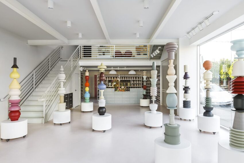 Art gallery interior with tall, colorful, abstract sculptures on round pedestals and a display counter in the background.