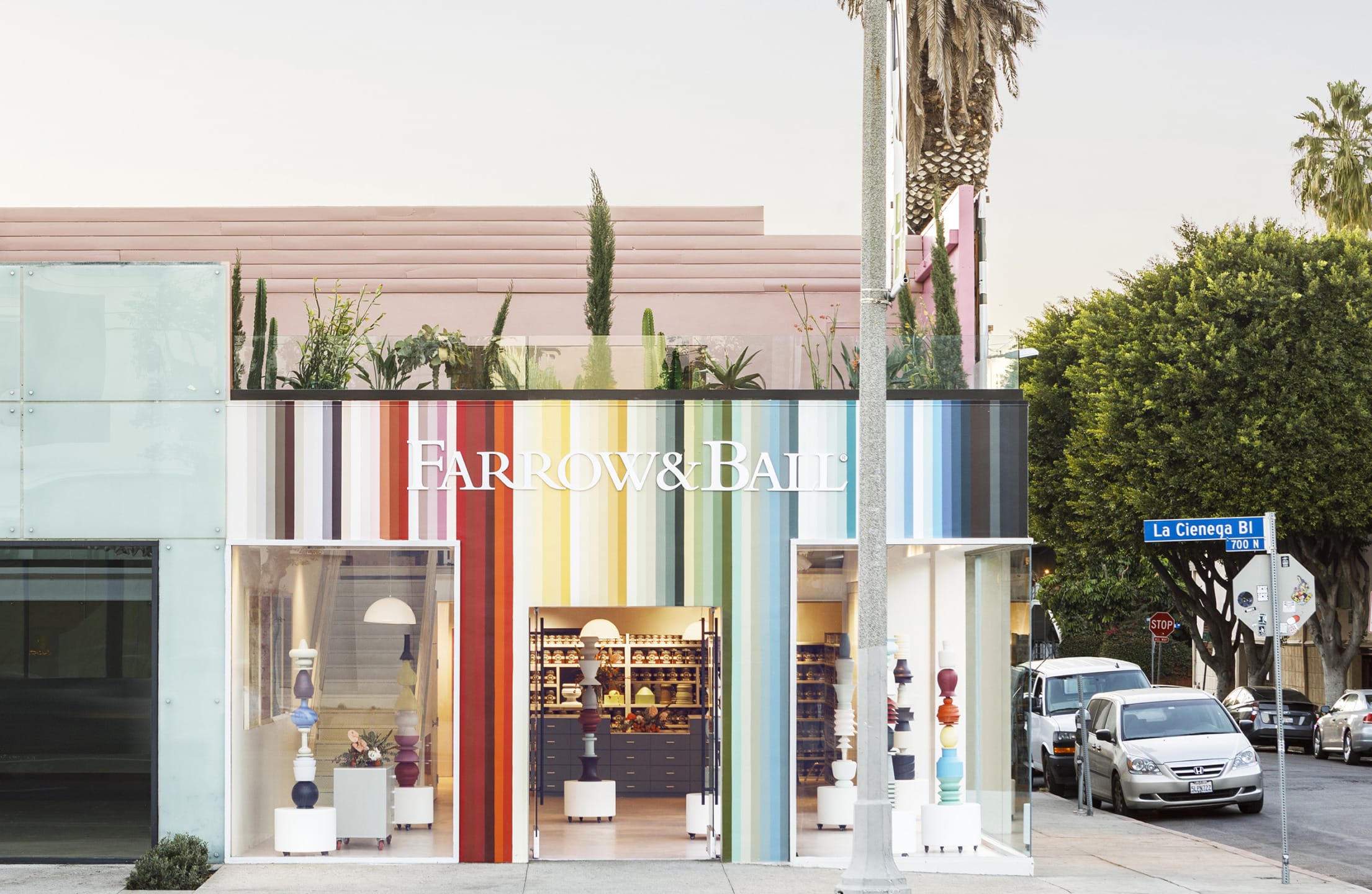 Storefront with colorful striped facade, displaying "Farrow & Ball" signage, located on a street with parked cars.