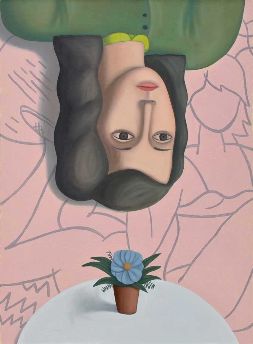 Upside-down portrait of a woman with dark hair, green shirt, and pink background with a potted blue flower in the foreground.