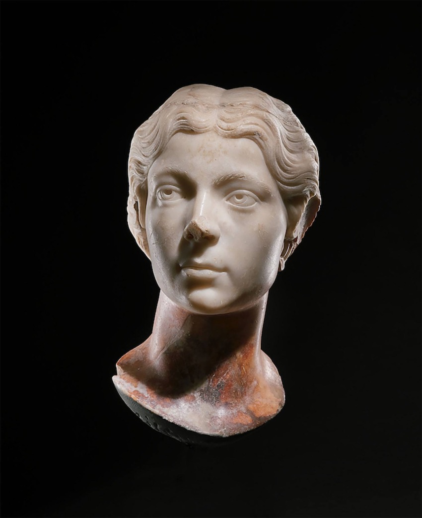Marble bust of a woman with intricate hair detail displayed against a dark background.