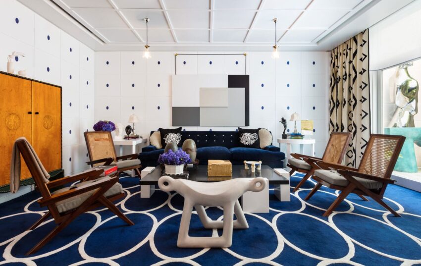 Modern living room with geometric decor, blue and white theme, abstract art, stylish chairs, and vibrant accents.