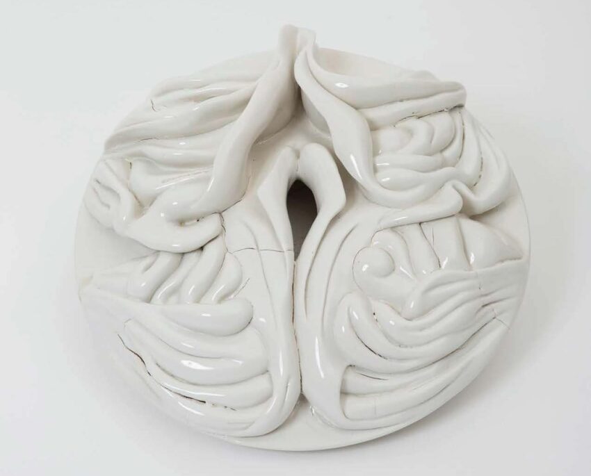 Abstract white ceramic sculpture with flowing, organic shapes and a central opening, displayed on a plain background.