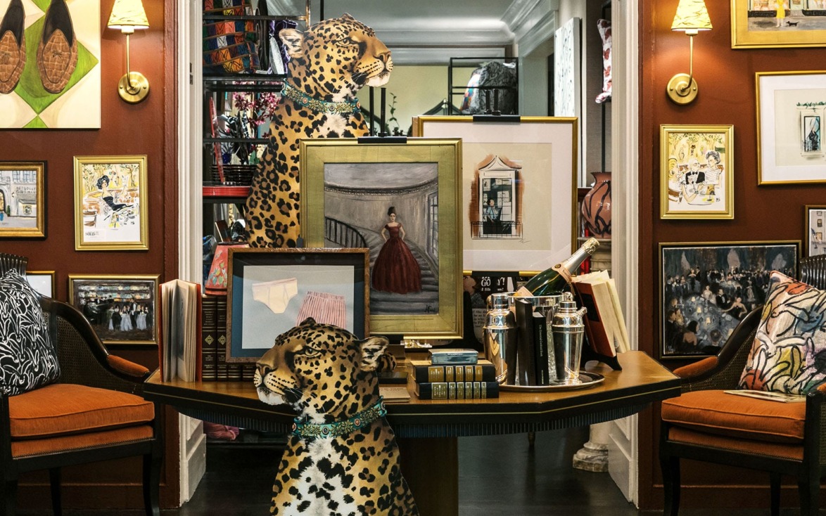 Eclectic room with leopard statues, framed artwork, and decorative items on a table against a warm, art-filled backdrop.