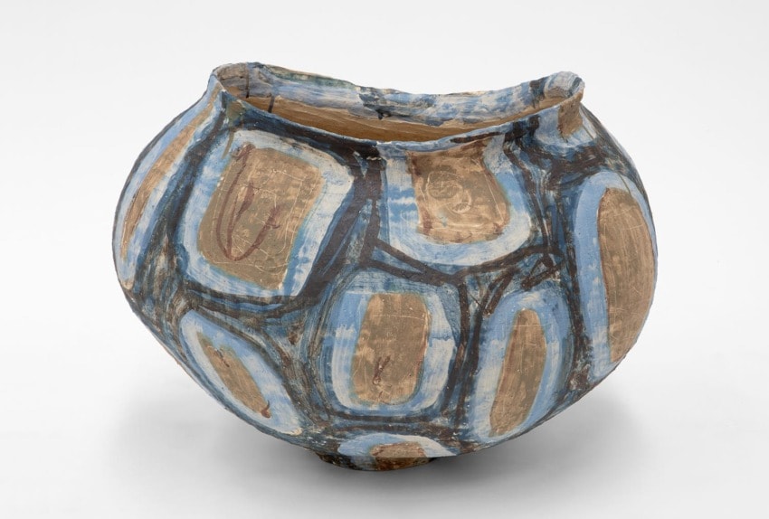 Painted ceramic pot with blue and brown geometric patterns on a white background.