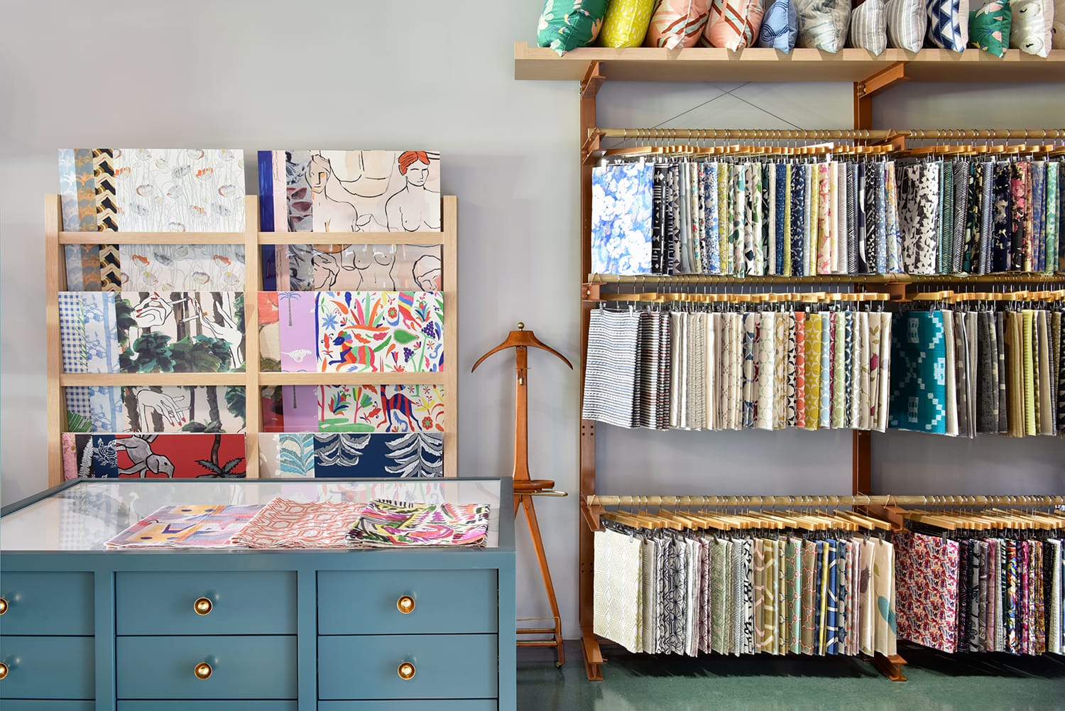 Fabric store with colorful textile samples on display racks and a blue counter with drawers in the foreground.