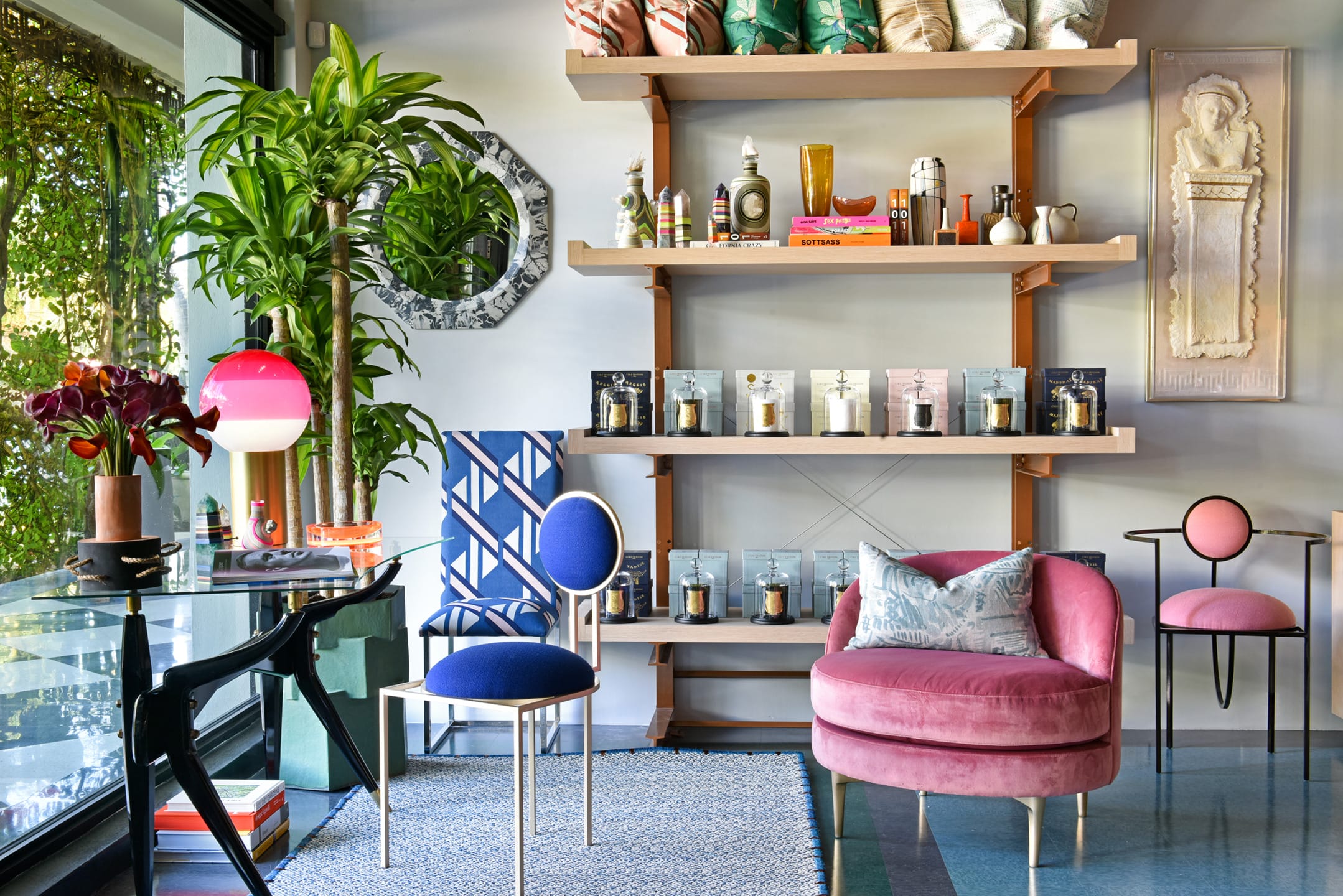 Colorful eclectic living room with modern chairs, plants, decorative items, and a large window letting in natural light.