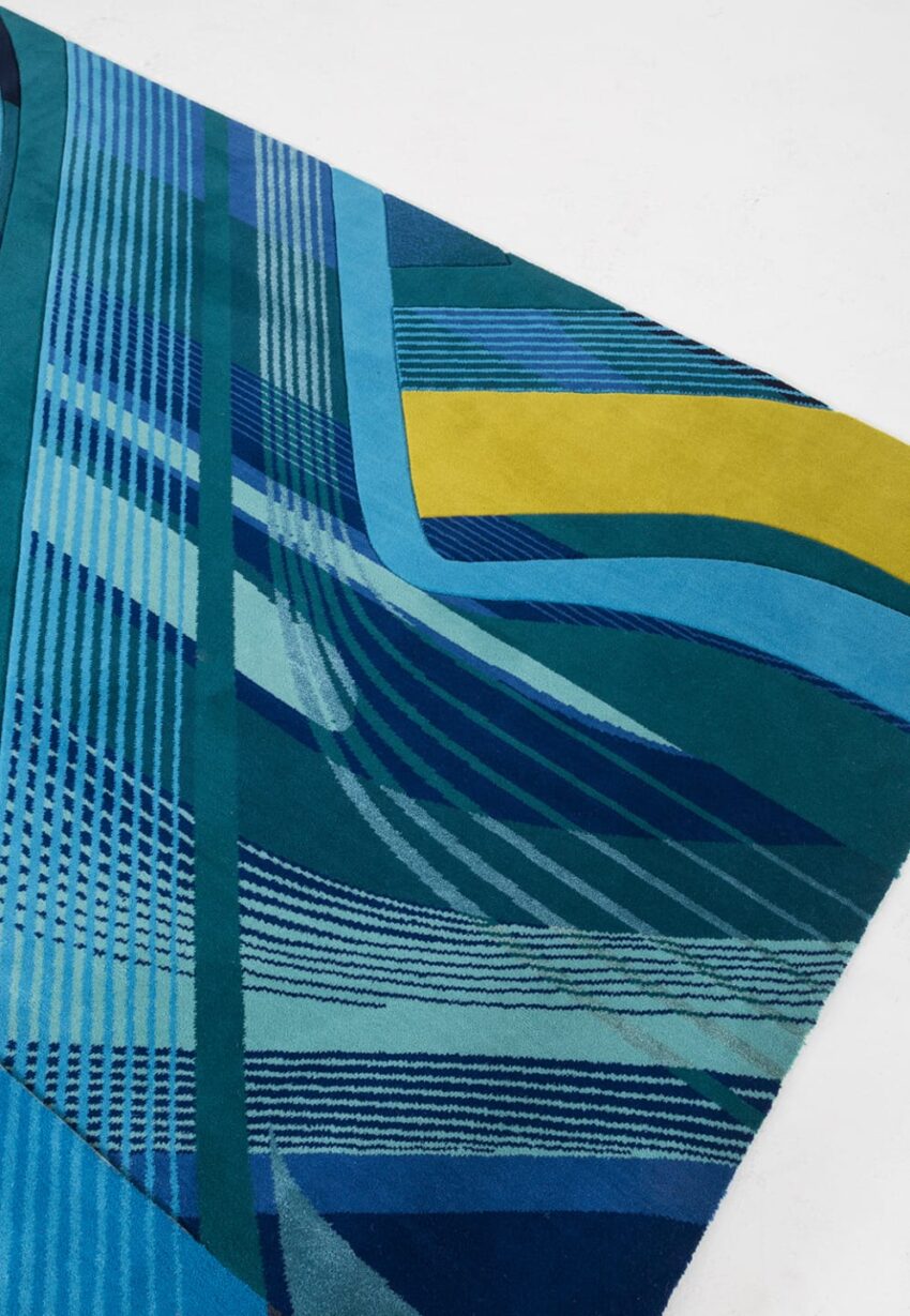 Abstract geometric blue and green rug with yellow accents and striped patterns on a white background.