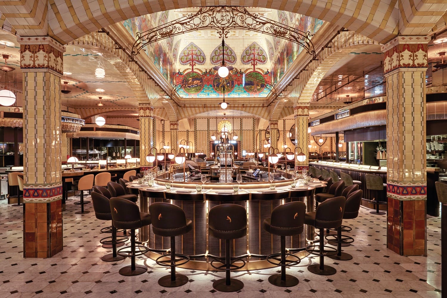 Art deco restaurant interior with stained glass ceiling, elegant bar, and black chairs, showcasing luxurious vintage design.