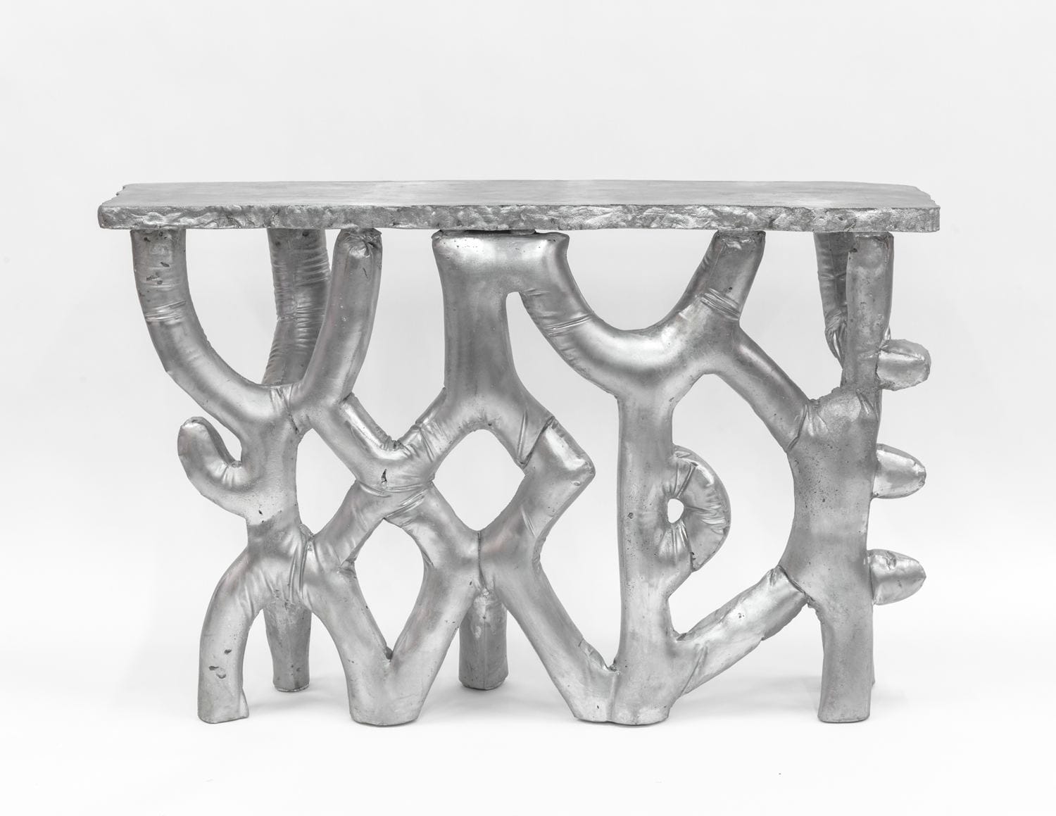 Abstract silver metallic bench with branch-like design against a white background.