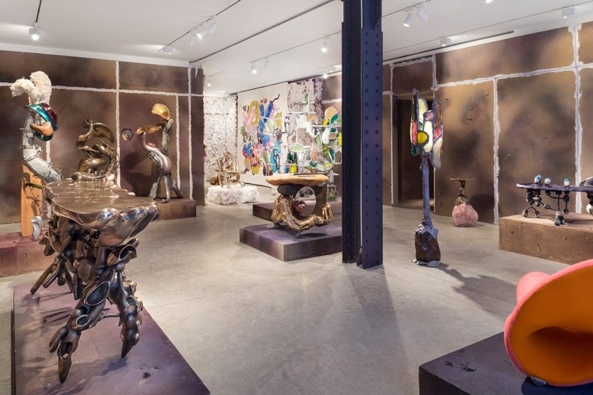 Art gallery interior with eclectic sculptures and paintings displayed on walls and platforms. Modern and abstract art theme.