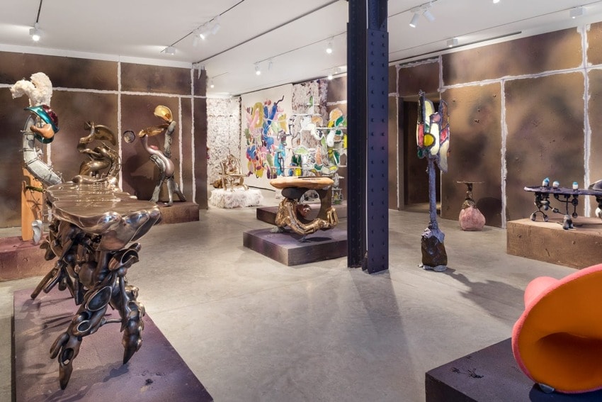 Art gallery interior with eclectic sculptures and paintings displayed on walls and platforms. Modern and abstract art theme.