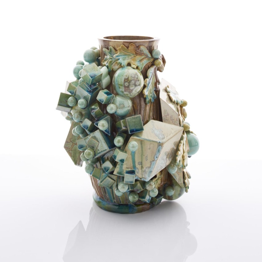 Intricately designed ceramic vase with geometric and organic shapes in shades of green and blue on a white background