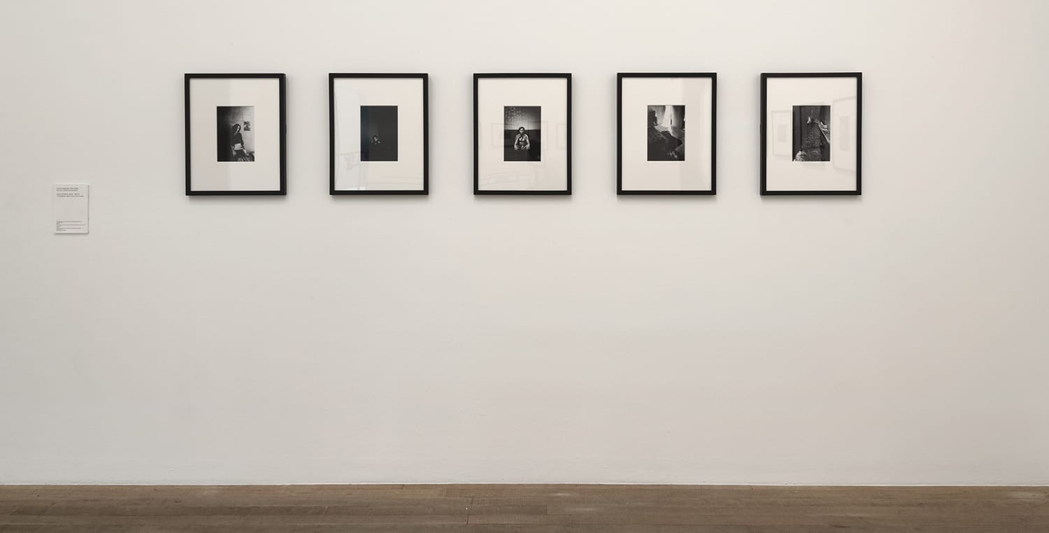 Gallery wall with five framed black and white photographs displayed in a row on a white wall.