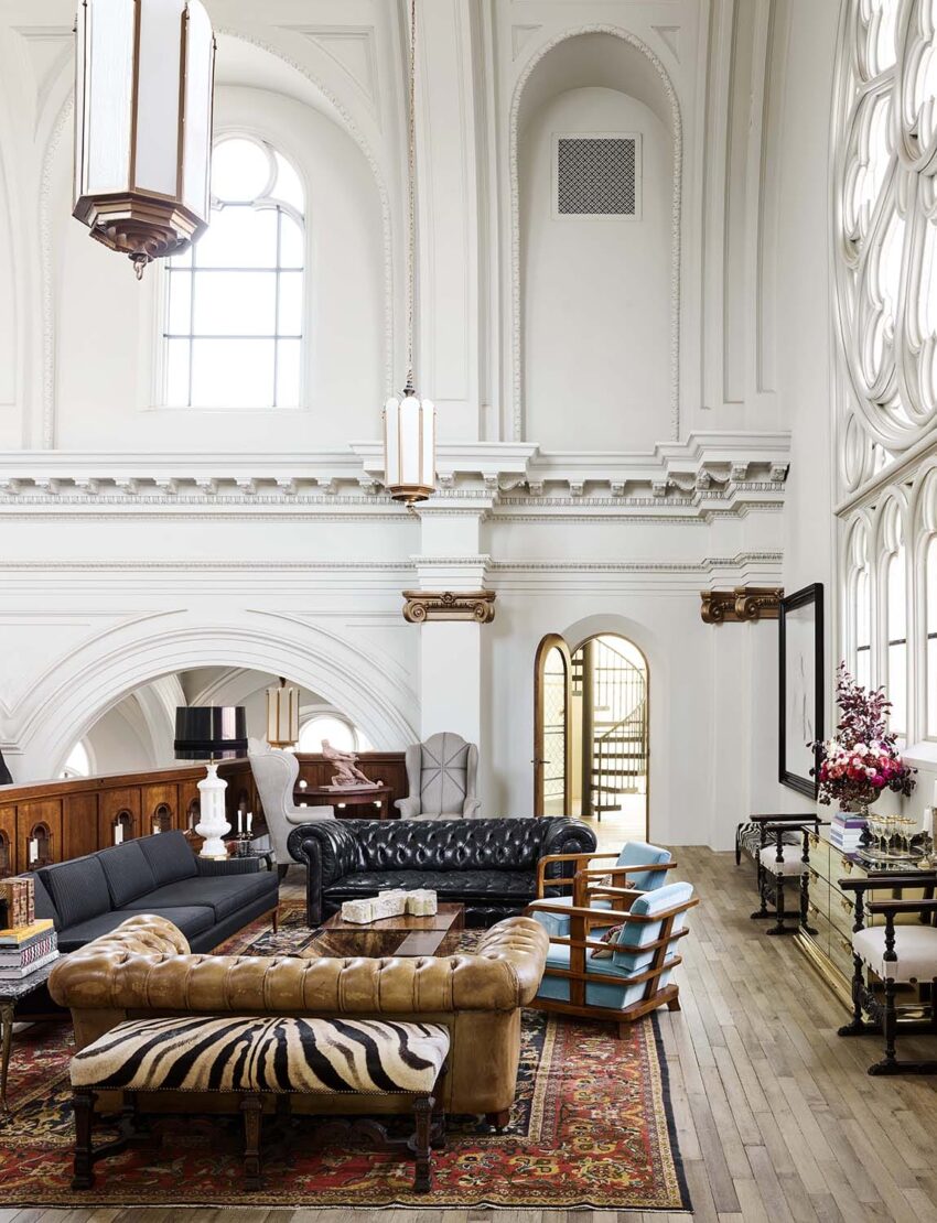 Luxurious living room with high ceilings, vintage furniture, large windows, and elegant decor.
