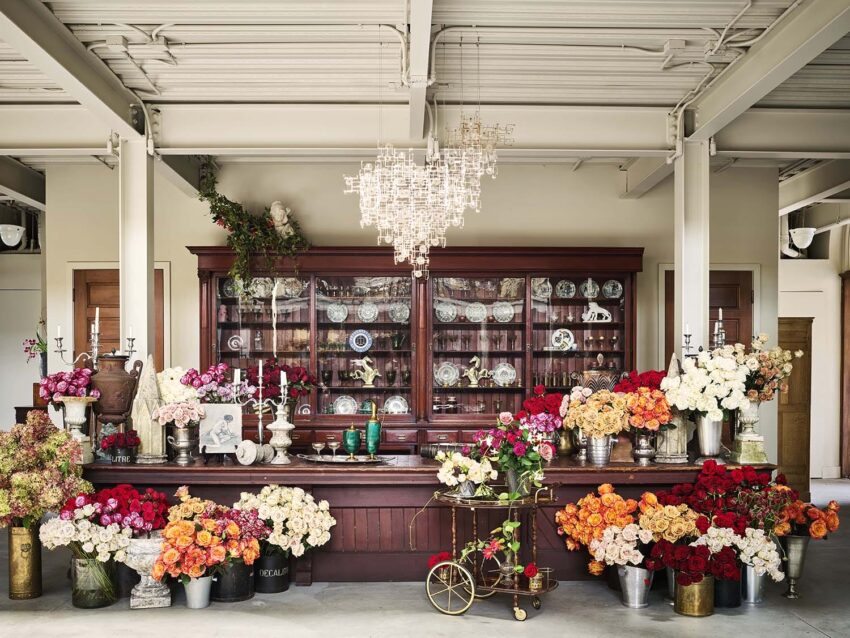 Floral shop interior with colorful flower arrangements on a wooden counter under a chandelier.