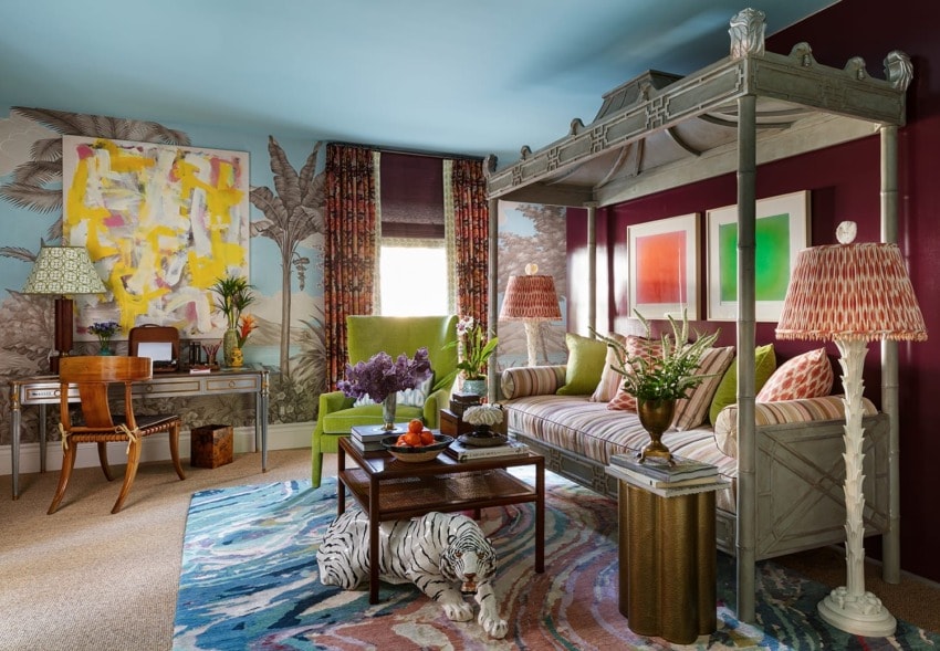 Eclectic living room with colorful decor, abstract art, green armchair, striped sofa, wooden desk, and unique patterned rug.