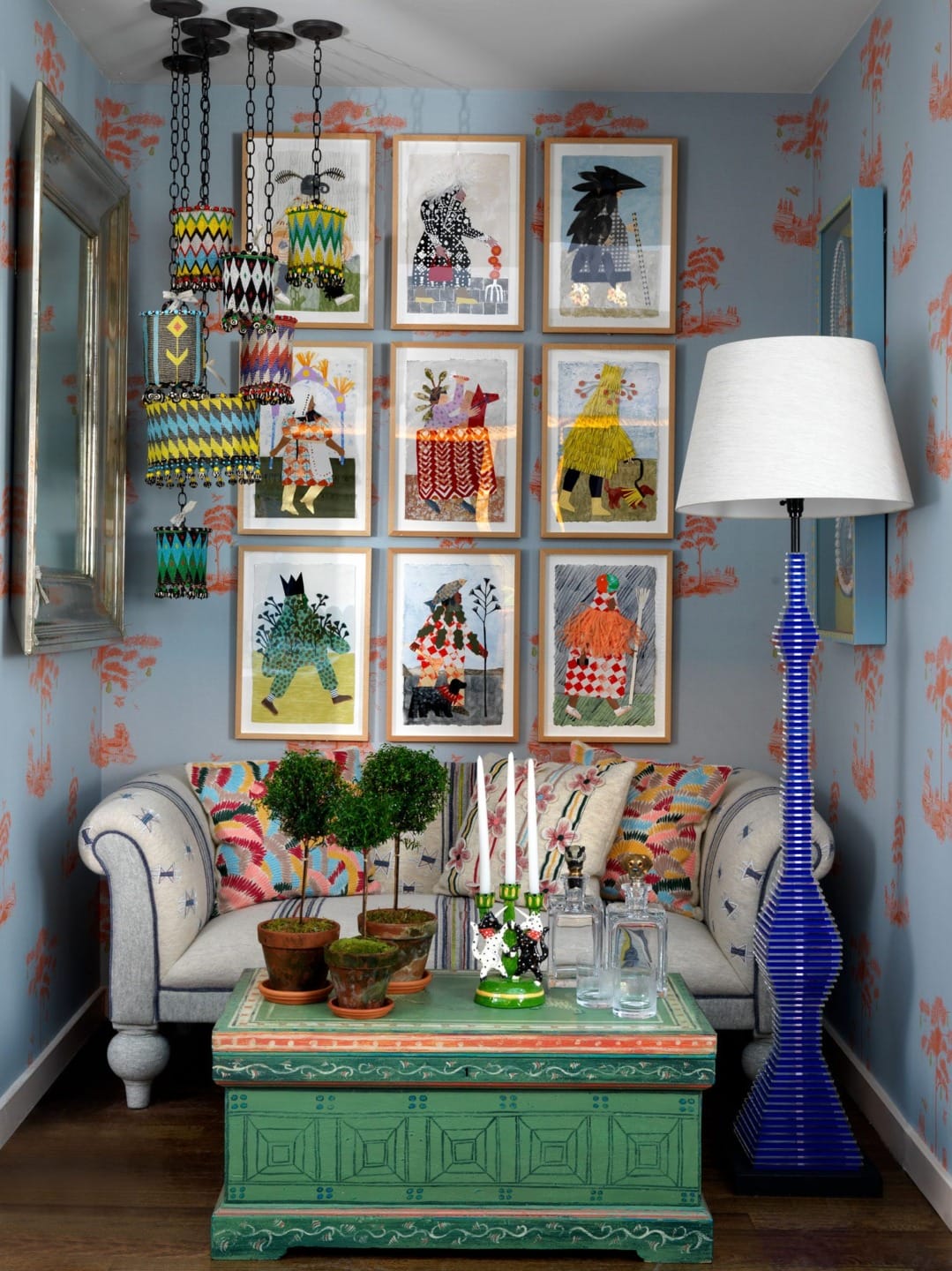 Colorful living room with patterned wall art, cozy sofa, unique pendant lights, green coffee table, and white floor lamp.