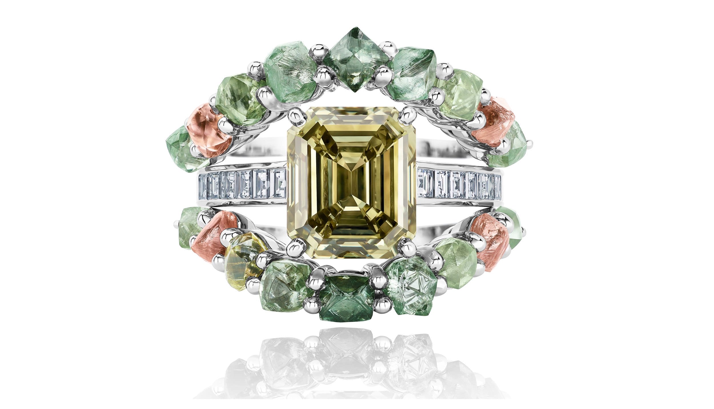 Intricate ring with large yellow gemstone in center, surrounded by green and pink stones on a reflective surface.