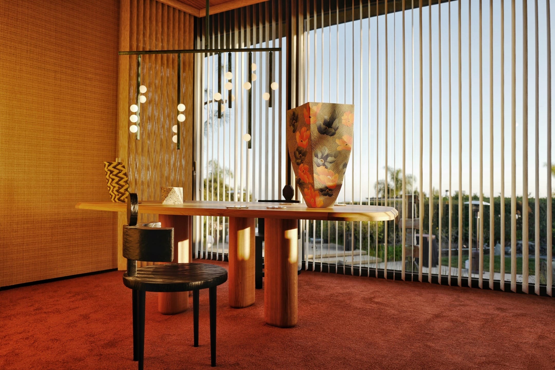 Modern interior with a wooden table, chair, decorative vases, pendant lights, and large windows with vertical blinds.