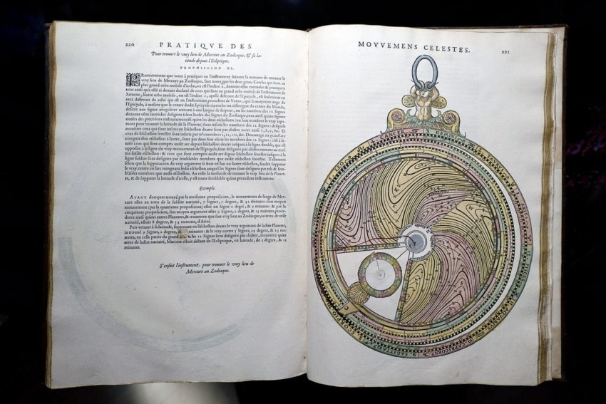 Historical book pages featuring an illustration of a complex circular celestial instrument and text on astronomical concepts.