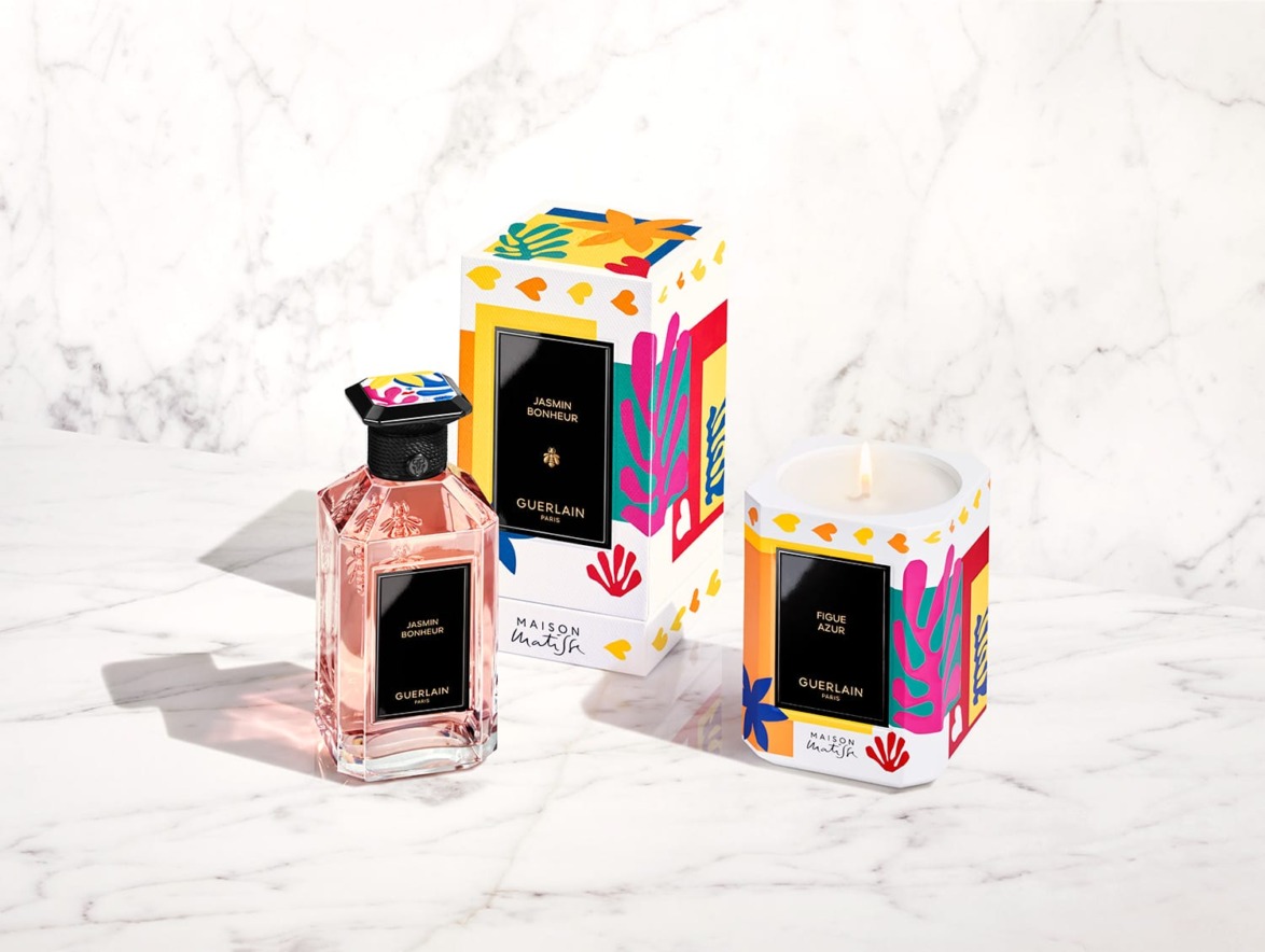Perfume bottle and decorative candle box with colorful designs on a marble surface.