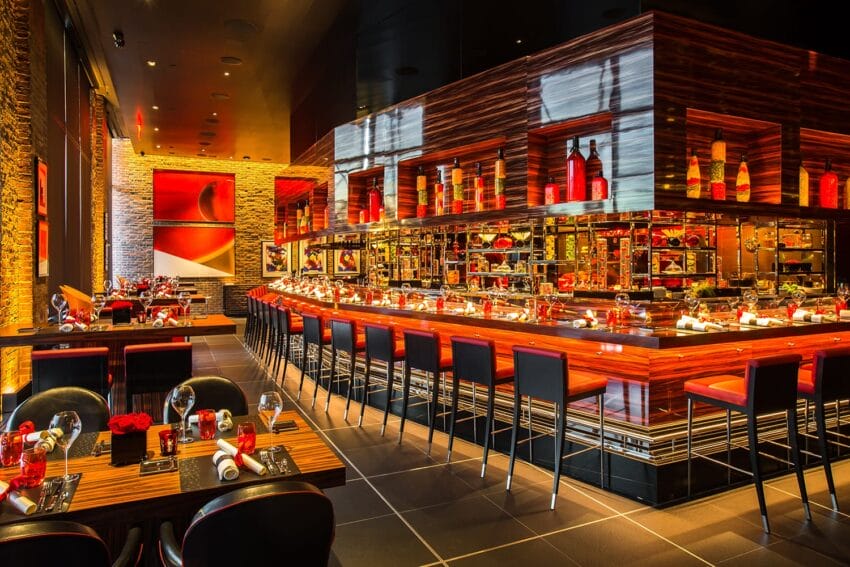 Modern restaurant interior with vibrant lighting, sleek bar, stylish seating, and artful decor.