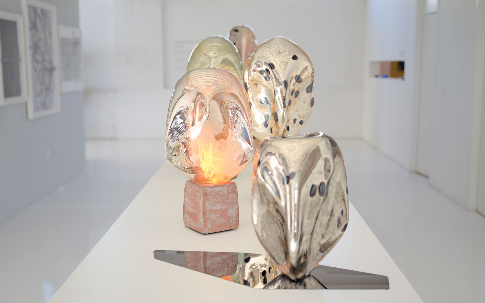 Silver and ceramic abstract sculptures on display in a well-lit gallery setting.