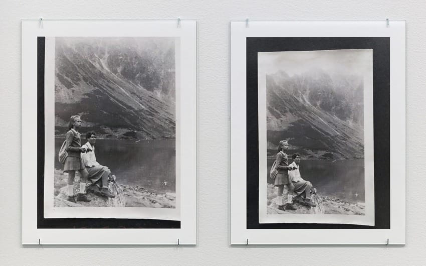 Two framed vintage photographs of a couple seated by a mountain lake, displayed on a white wall.