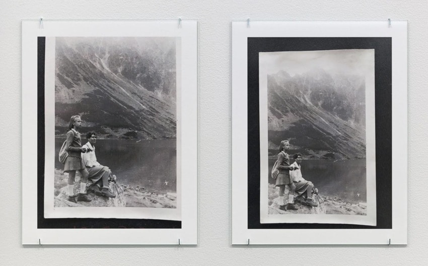 Two framed vintage photographs of a couple seated by a mountain lake, displayed on a white wall.