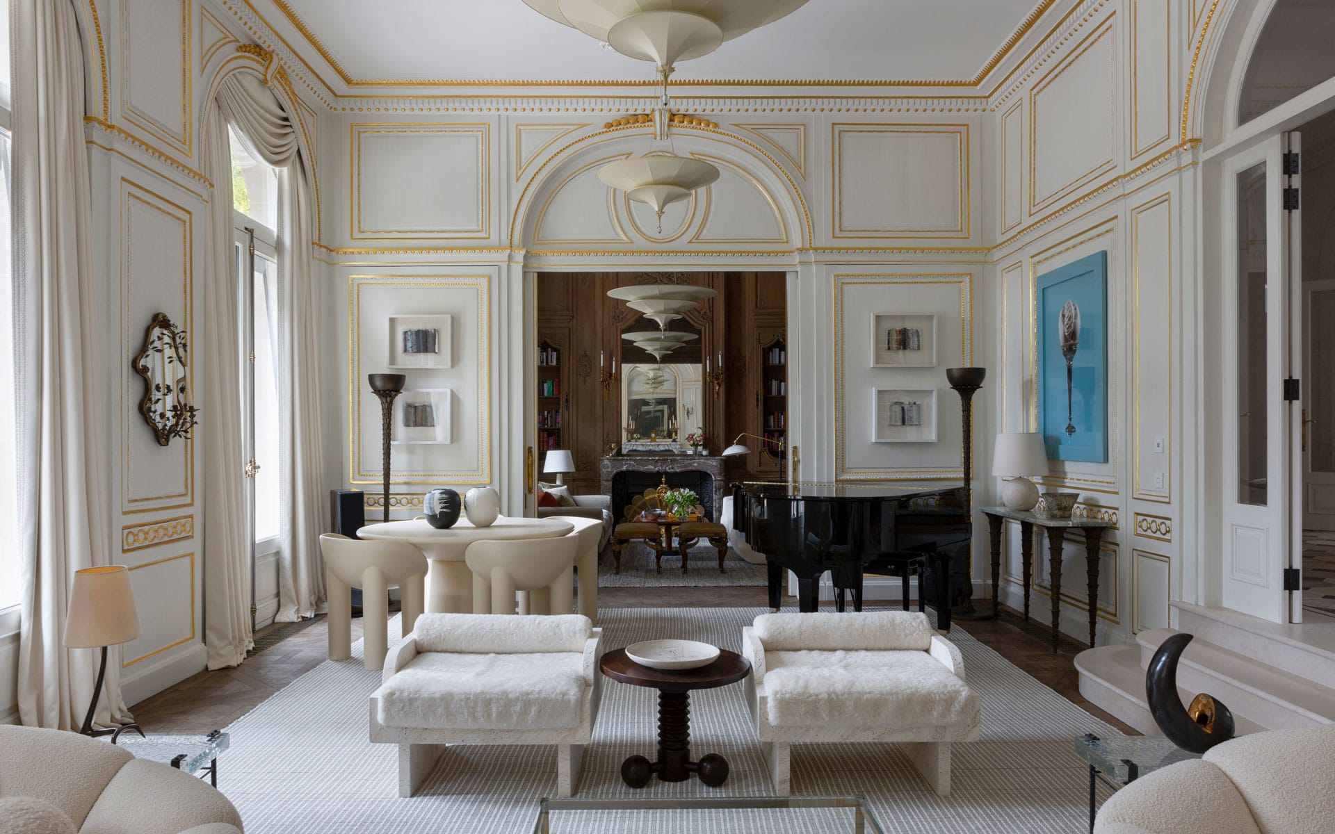 Elegant living room with luxurious white and gold decor, plush seating, grand piano, and large mirrors reflecting the space.