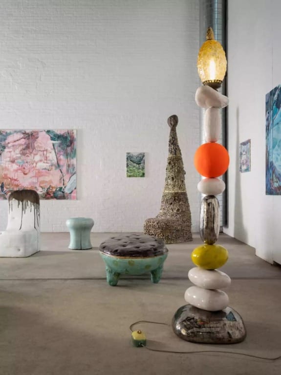 Contemporary art installation featuring abstract sculptures and unique furniture in a white-walled gallery space.