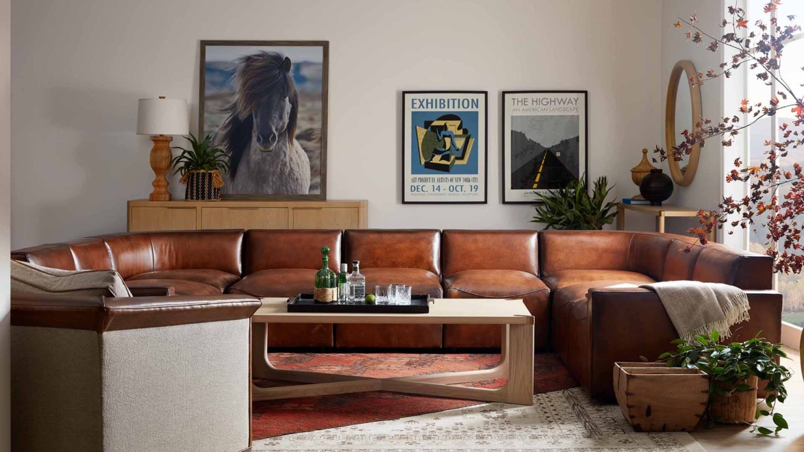 Cozy living room with a large brown leather sectional sofa, stylish decor, and wall art displayed in a well-lit setting.