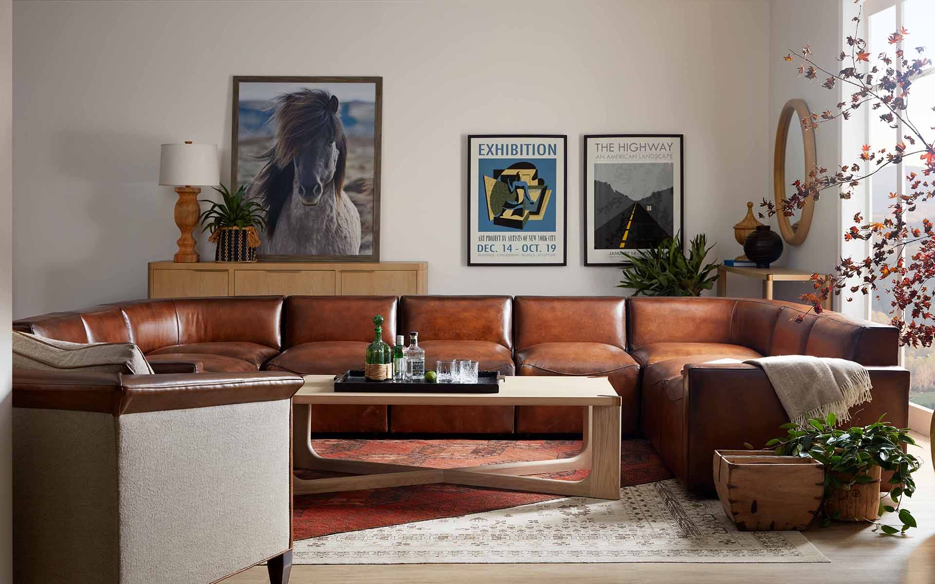 Cozy living room with a large brown leather sectional sofa, stylish decor, and wall art displayed in a well-lit setting.