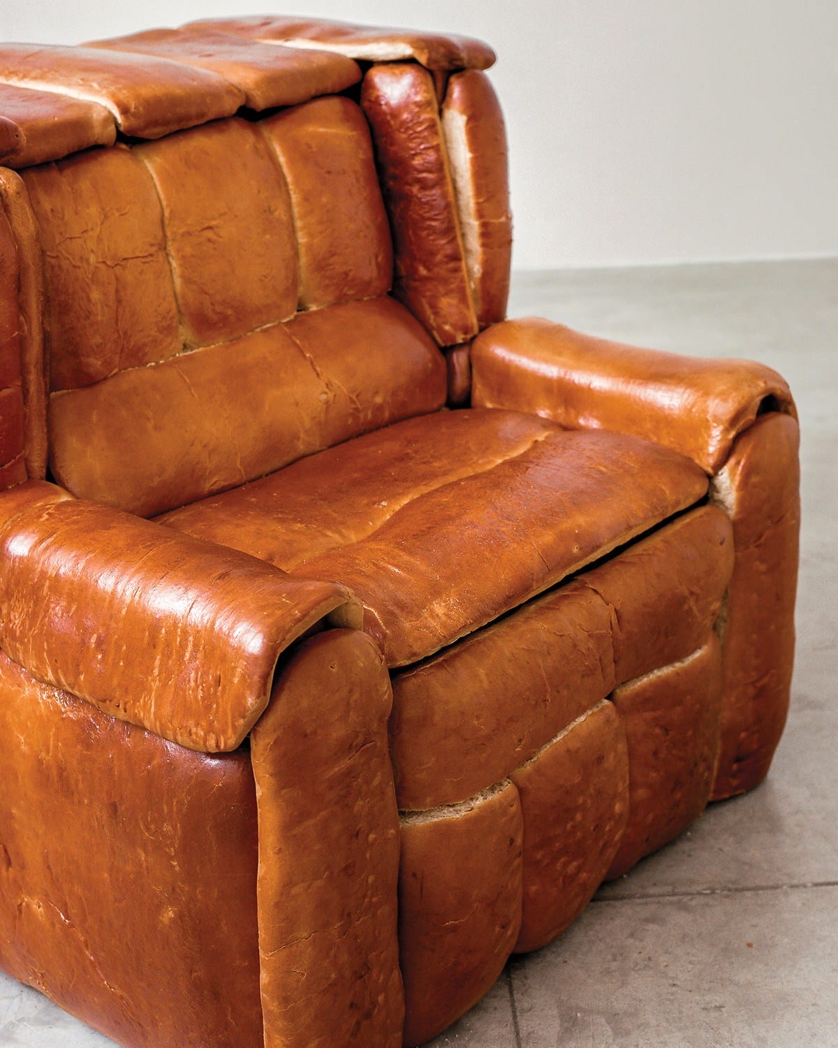Armchair covered in realistic bread texture, placed in a minimalist room with a light floor.