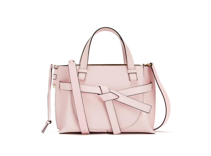 Pink handbag with a unique strap design and shoulder strap, featuring a modern and stylish look.
