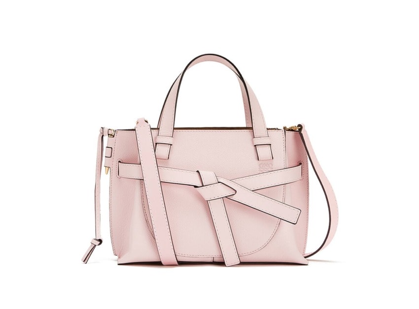 Pink handbag with a unique strap design and shoulder strap, featuring a modern and stylish look.