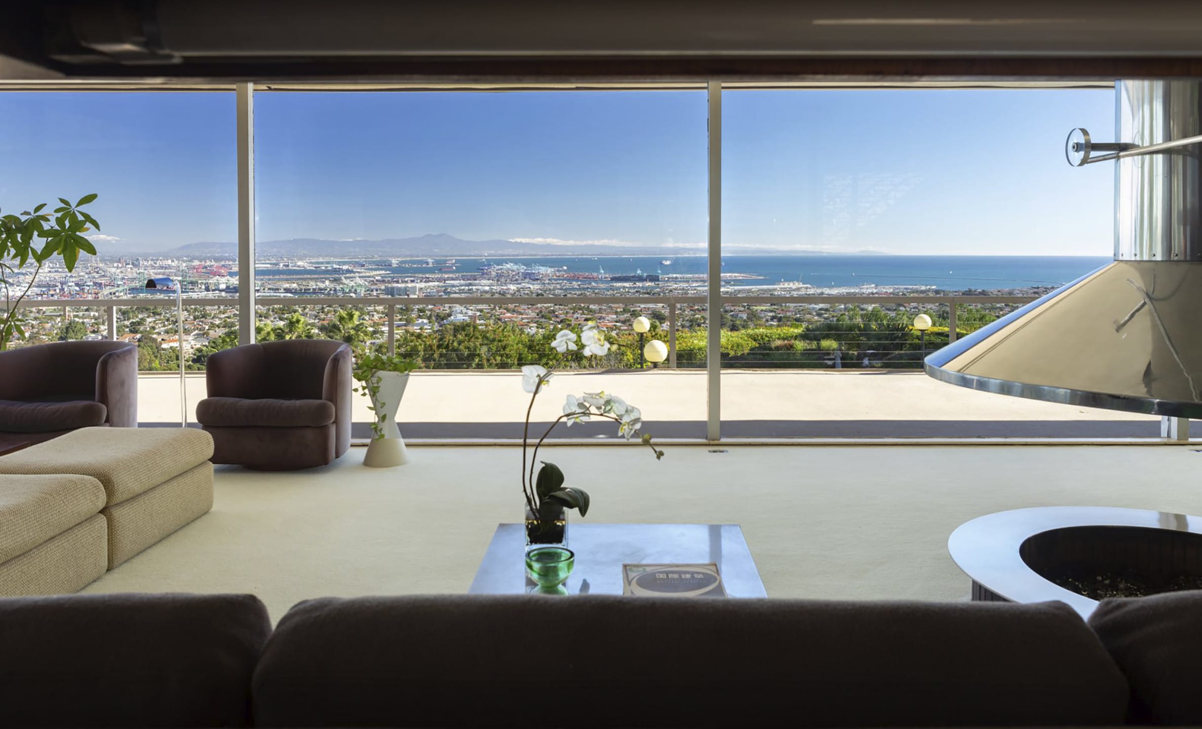 Spacious living room with modern furniture, large windows showing a scenic ocean view.
