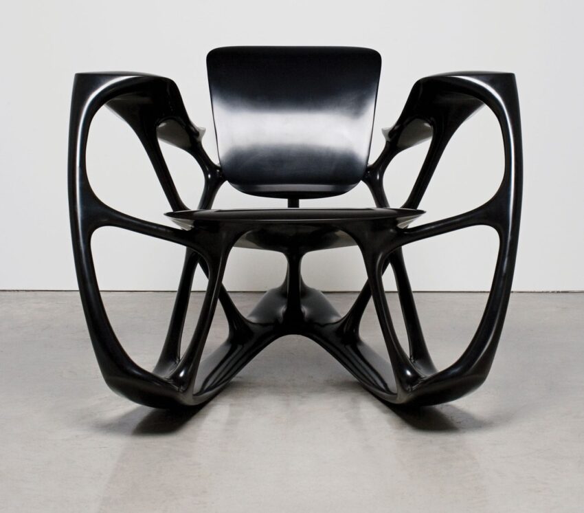 Sleek modern black chair with unique sculptural design and open frame on a light gray floor background