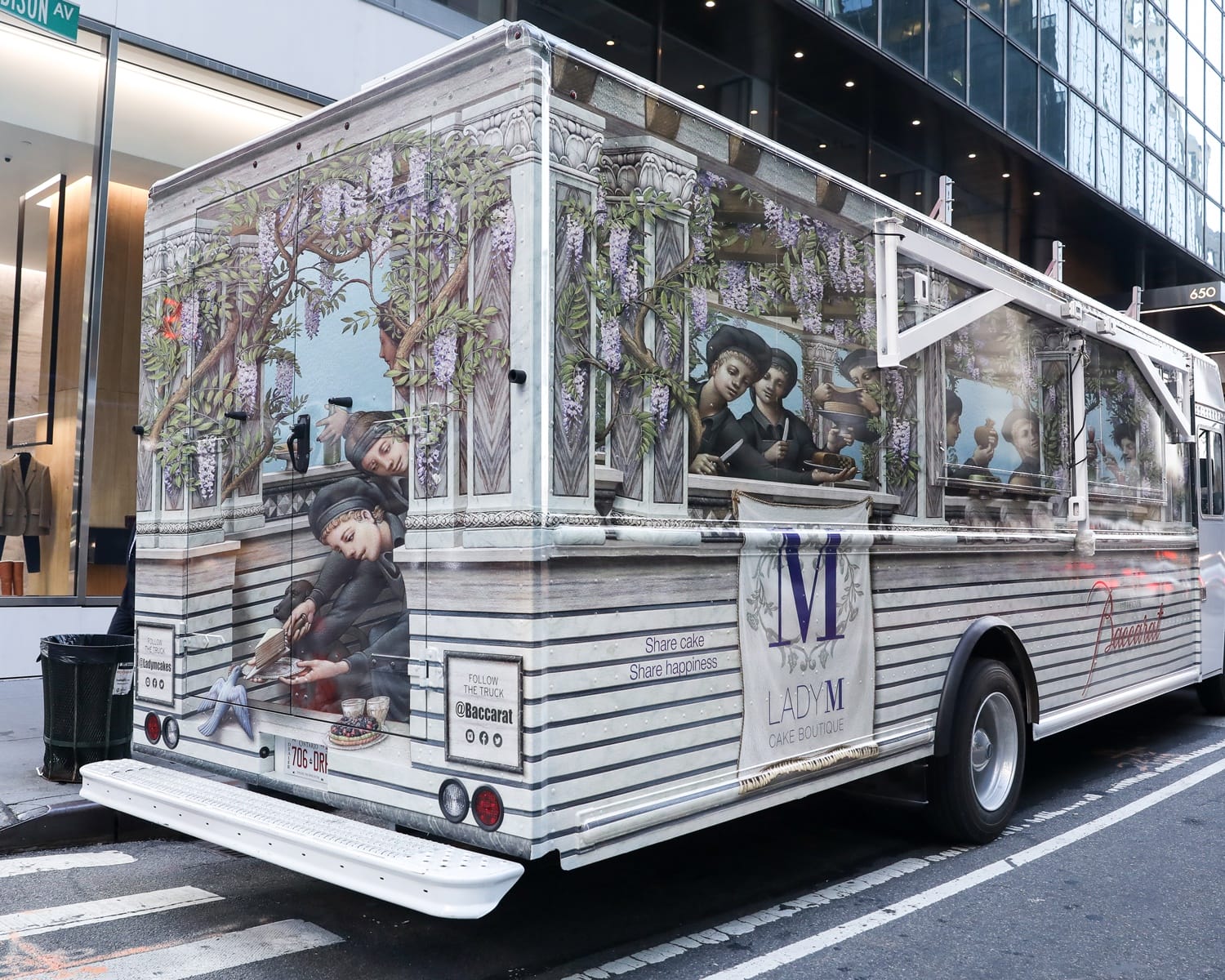 Decorated food truck with a whimsical illustration of people enjoying desserts under ornate architecture on a city street.