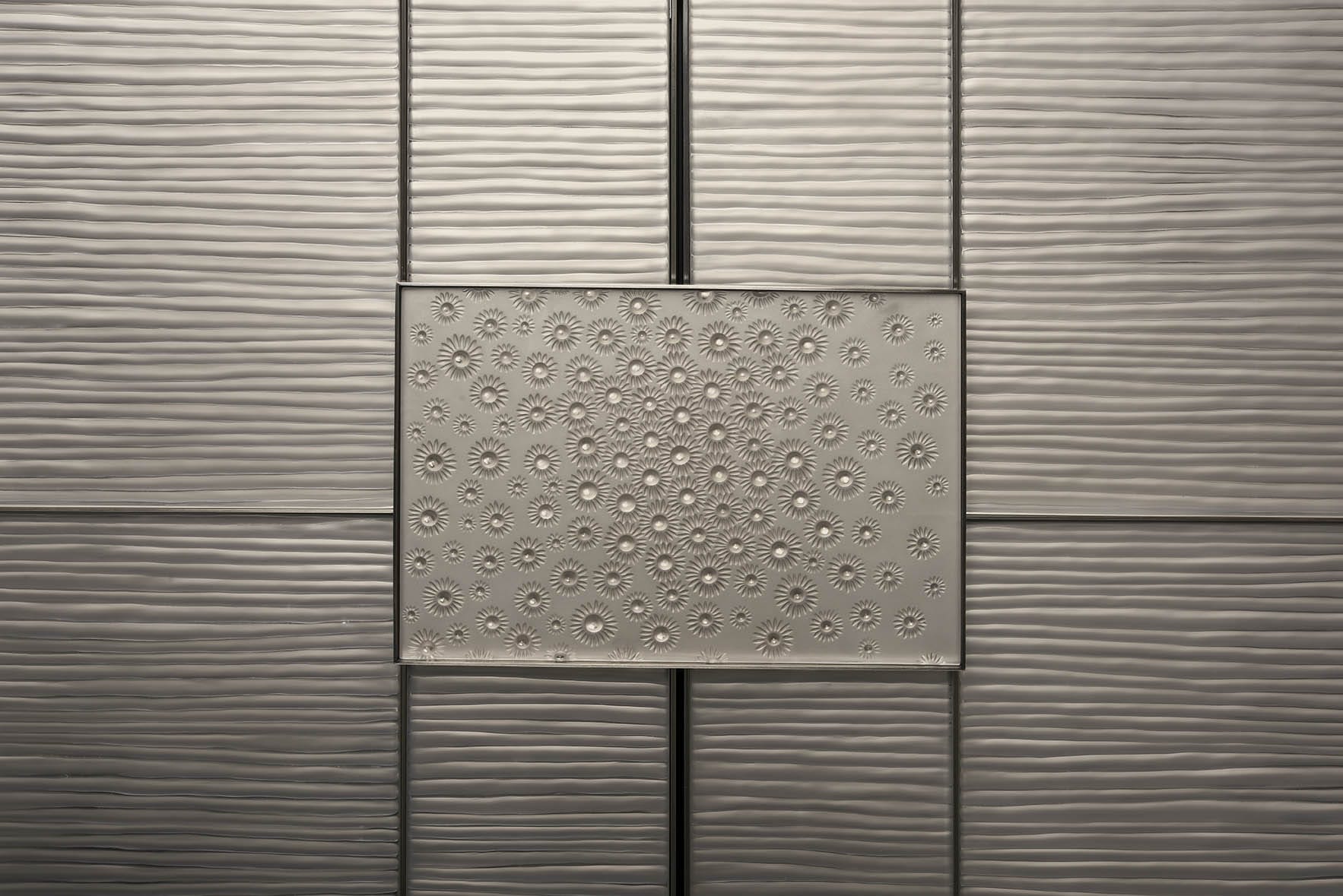 Textured metallic wall with a decorative central panel featuring embossed star-like patterns.