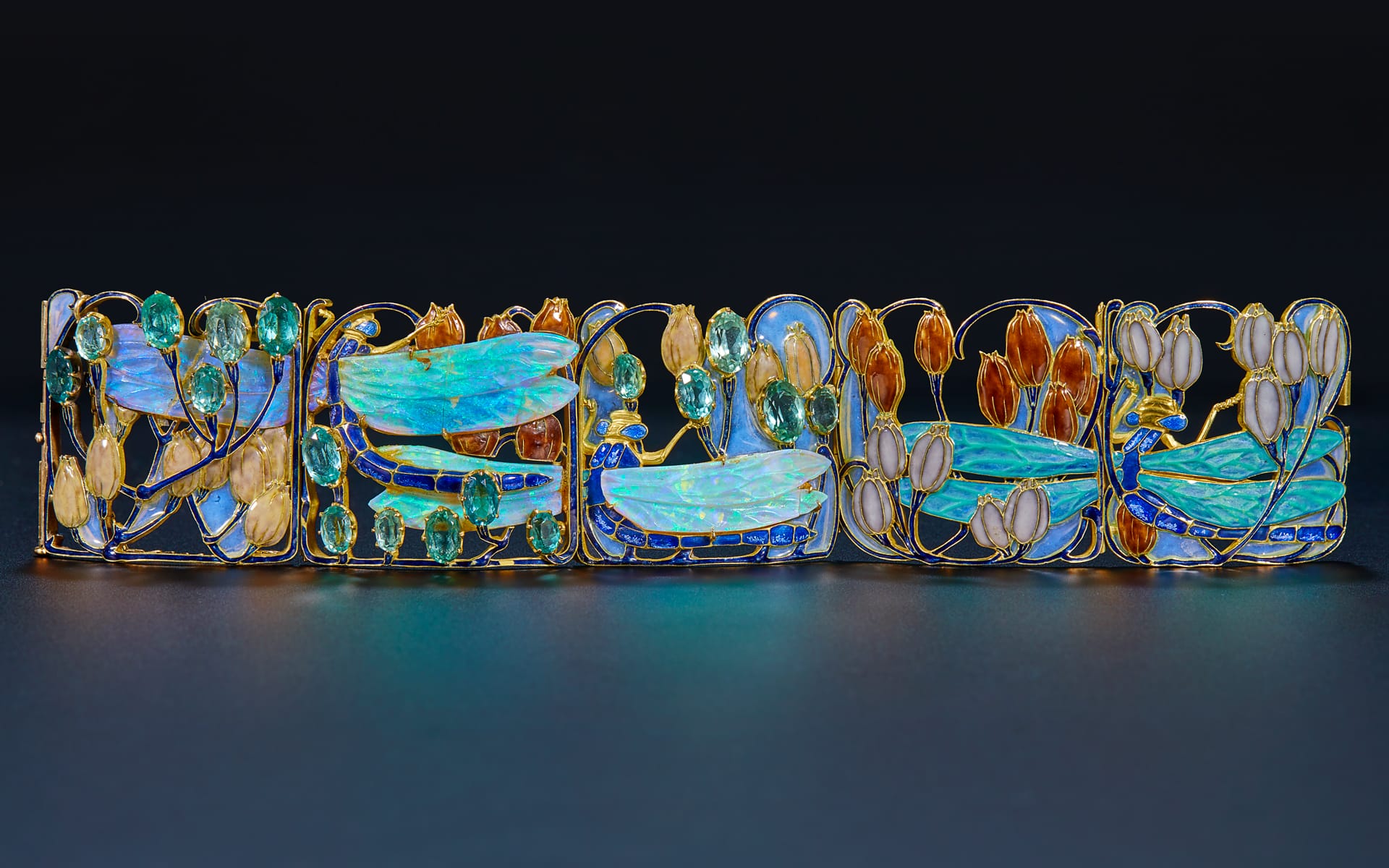 Artistic bracelet with colorful gemstones and intricate design on a dark background.