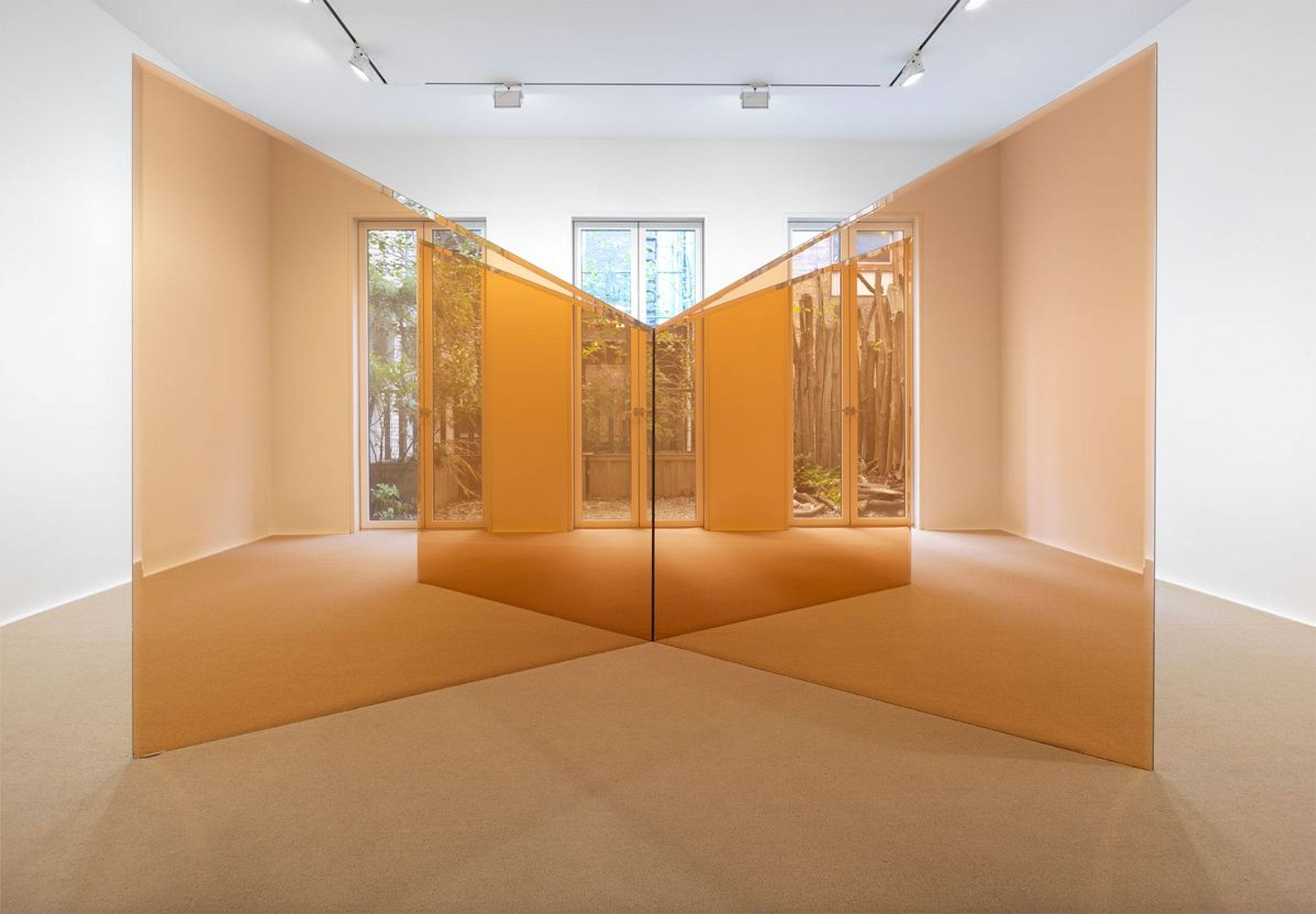 Contemporary art installation with mirrored walls and fabric, creating reflections in a minimalist gallery space.