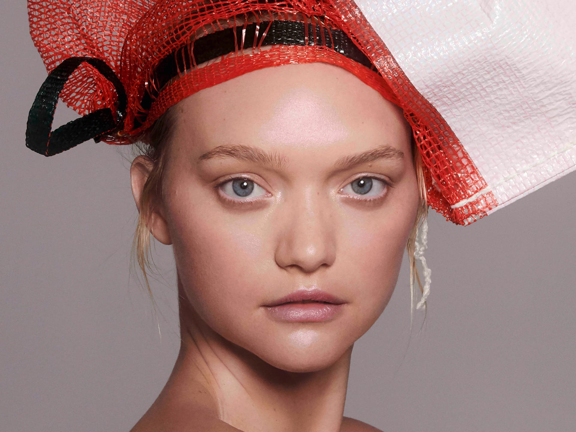 Person with artistic red and white headwear posing against a neutral background.