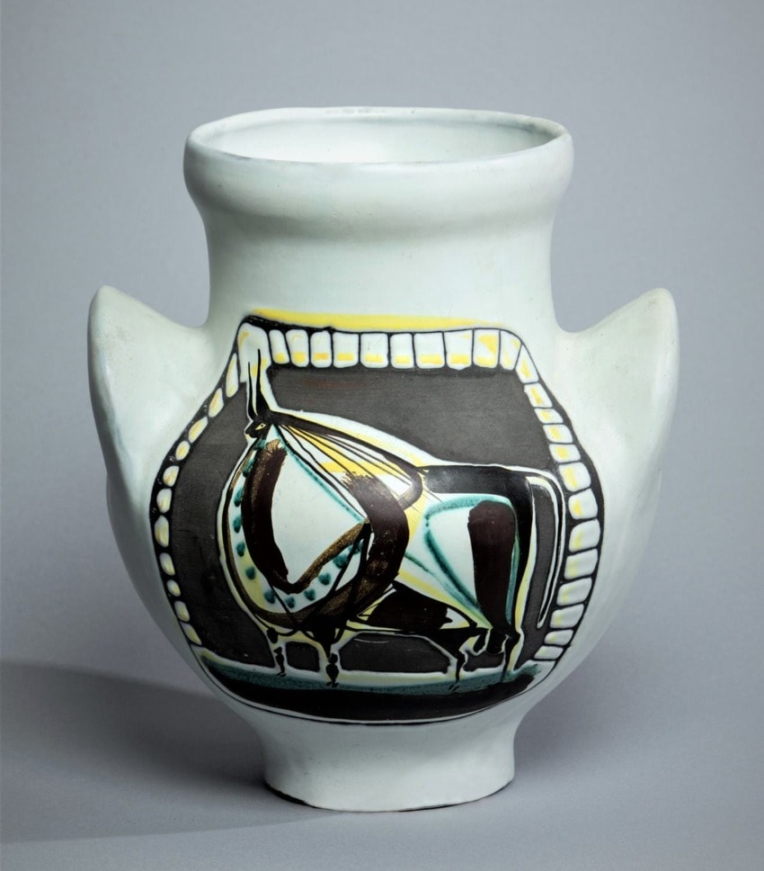 Ceramic vase with a painted abstract horse design, featuring wide handles and a circular opening on a gray background.