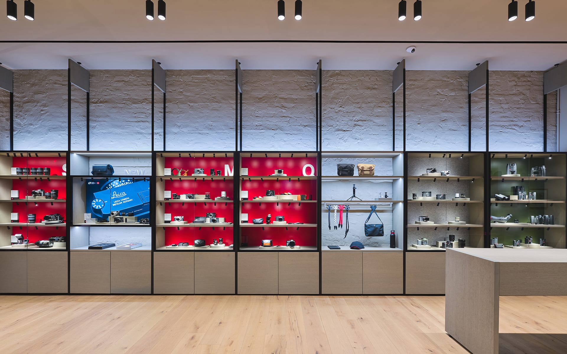 Camera store interior showcasing various lenses and accessories on illuminated shelves against a brick wall background.