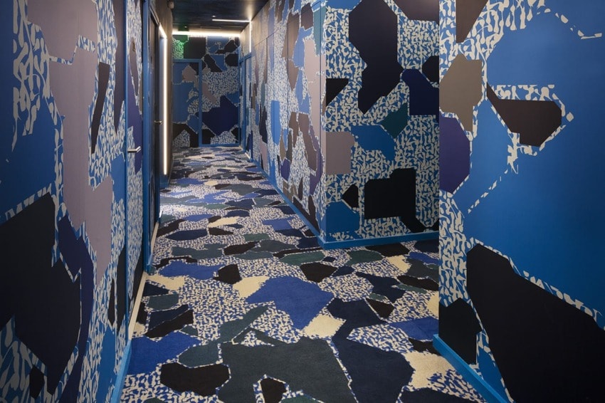 Colorful abstract patterned hallway with geometric shapes in shades of blue, black, and white on walls and floor.